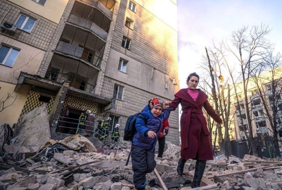A woman with a child evacuates from a residential building damaged by Russian shelling in Kyiv, Ukraine, March 16. (CNS/Reuters/State Emergency Service of Ukraine)