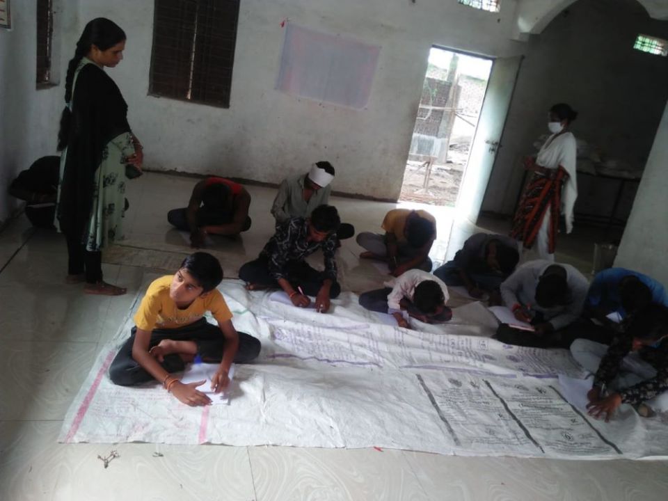 Boys in a rural village work on essays on the topic "How will I protect my sister?" (Courtesy of Celine Paramundayil)