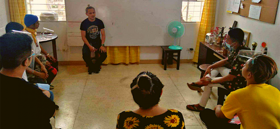 Young Filipino men sit in a circle indoors and discuss Second Chance program