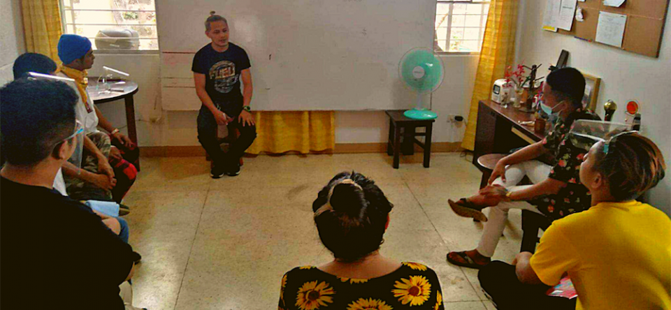 An alumnus of the Second Chance program speaks to the program's current participants at a weekend training at the program's office. (Courtesy of the Missionaries of Mary) Young Filipino men sit in a circle indoors and discuss Second Chance program