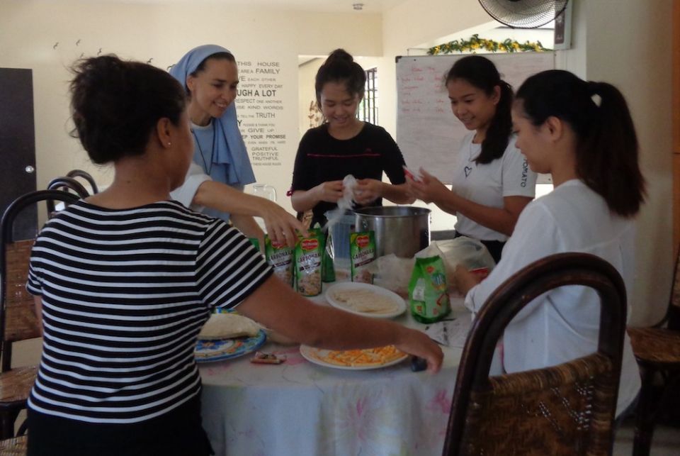 A Catholic sister and young girls around a table make food