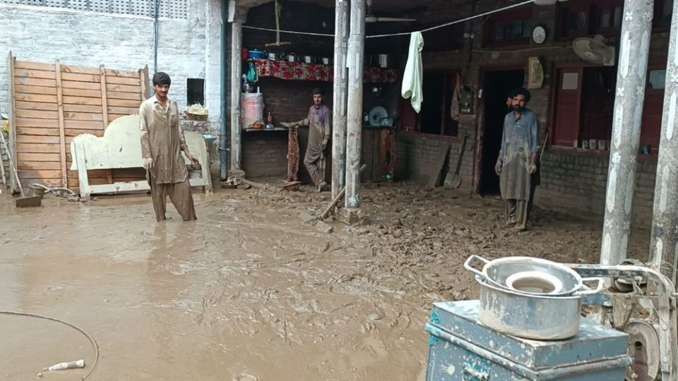 Mohammad Zahid (right) and his brothers look at his house in northern Pakistan's Swat Valley. "Within seconds, we were submerged in 4 to 5 feet of water," Zahid said. "I had to break the walls with a hammer to evacuate the family." (Amjad Gulzar)