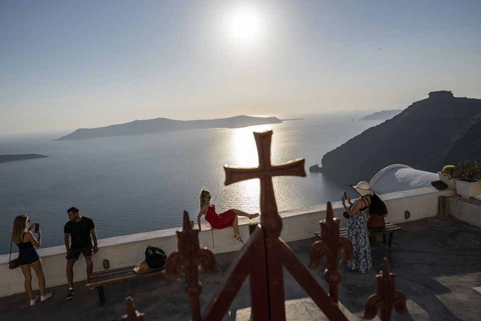 A woman poses for a photograph outside the wrought-iron enclosure of the Dormition of the Virgin Mary Catholic Church on the Greek island of Santorini June 15. (AP/Petros Giannakouris)