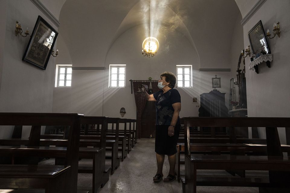 Parishioner Maria Tsagorari holds an incense burner inside the Dormition of the Virgin Mary Catholic Church on the Greek island of Santorini June 15. Before coronavirus restrictions, she used to attend Mass regularly at the Monastery of St. Catherine. (AP