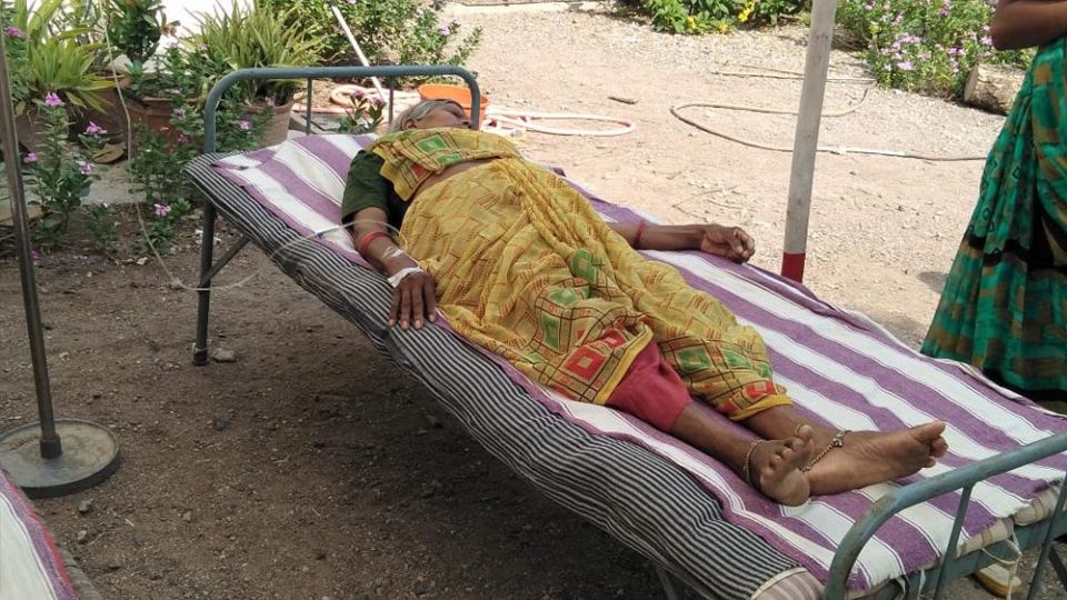 An elderly nun who has tested positive for COVID-19 lies on a cot in the shade outside Jyoti clinic in Chachana village, Gujarat, India. (Courtesy of Chetan Parmar)