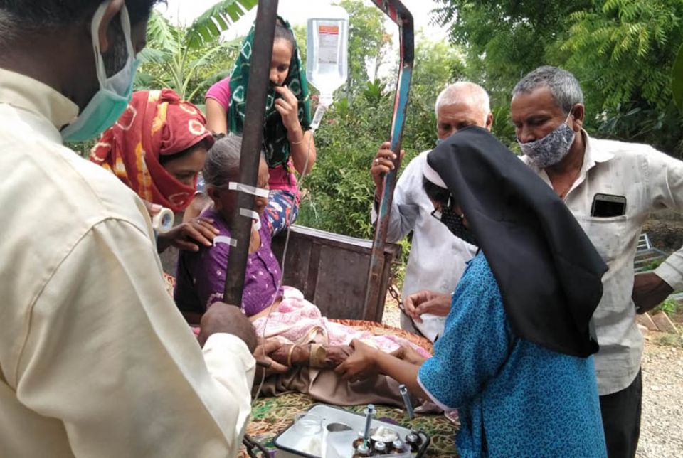 Fr. Ajeesh Chirayarikil, left foreground, helps Sr. Lisset Vadakkekara, at right in blue, administer an IV drip to a woman with COVID-19 symptoms in front of Jyoti clinic, managed by Congregation of Mother Carmel nuns at Chachana village in Gujarat, India Fr. Ajeesh Chirayarikil, left foreground, helps Sr. Lisset Vadakkekara, at right in blue, administer an IV drip to a woman with COVID-19 symptoms in front of Jyoti clinic, managed by Congregation of Mother Carmel nuns at Chachana village in Gujarat, India