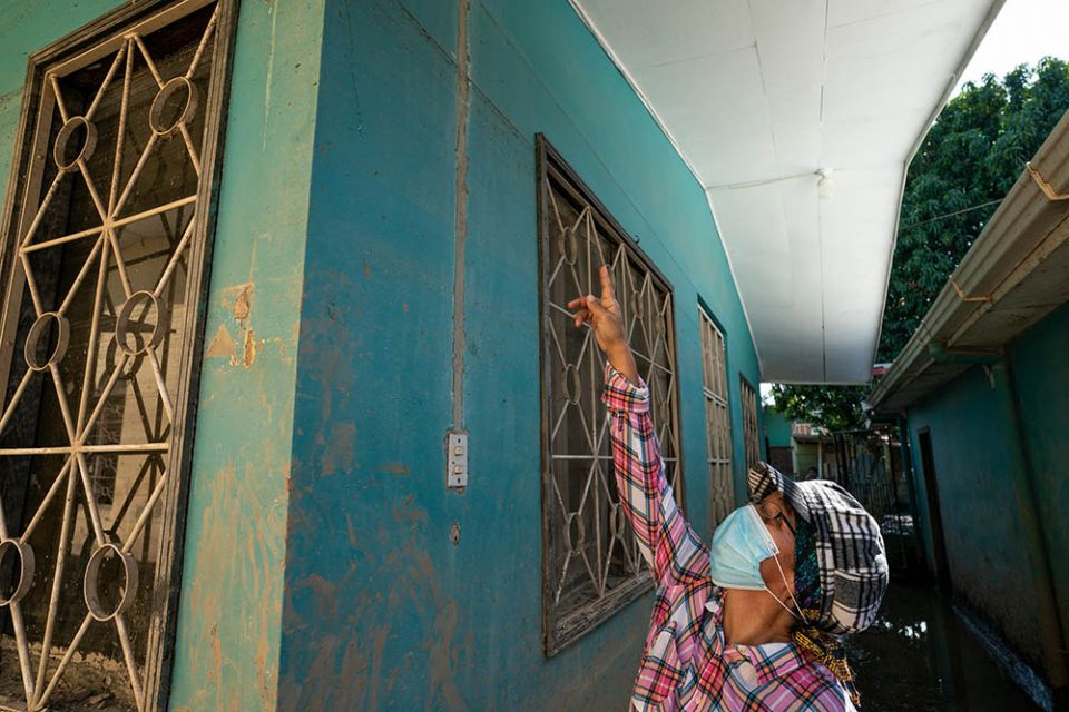 Sr. Victoria Emérita points to the floodwater line on a building at Our Lady of the Holy Fountain Nursery School in La Lima, Honduras. (Gregg Brekke)