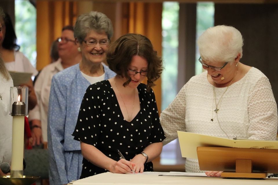 Sr. Katherine Frazier signs her profession document with Sr. Pat Siemen, right, prioress of the Adrian Dominican Sisters, at Frazier's first profession in August 2018. (Courtesy of the Adrian Dominican Sisters / Angela Kessler)