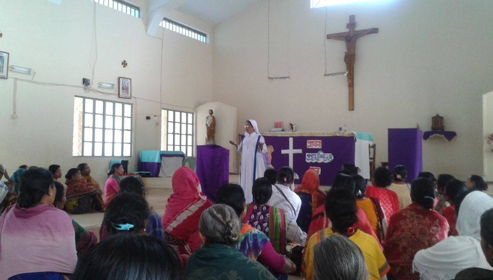 People gathered in a church listening to a Catholic sister