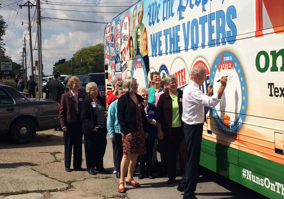 Vice President Joe Biden signs his name to the Network Nuns on the Bus official vehicle after speaking at the kickoff rally in front of the Iowa State Capitol in September 2014. Some of the Nuns on the Bus, including Sr. Simone Campbell, in red shoes, sta Vice President Joe Biden signs his name to the Network Nuns on the Bus official vehicle after speaking at the kickoff rally in front of the Iowa State Capitol in September 2014. Some of the Nuns on the Bus, including Sr. Simone Campbell, in red shoes, sta