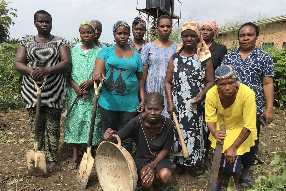 A group of indigent women pose with Sr. Catherine Nkereuwem (right, in blue print blouse) after weeding the farmland where they grow cassava behind the home in preparation for plowing and planting in Uyo, a town in southeastern Nigeria. (Valentine Iwenwan