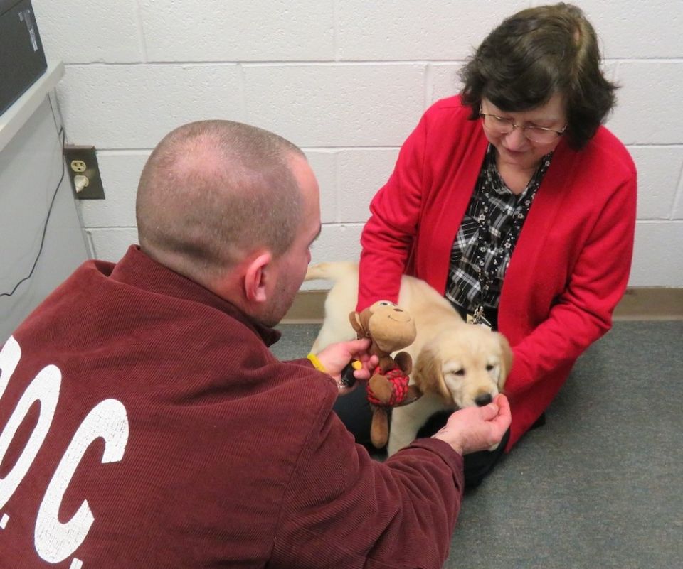 Benedictine Sr. Sue Fazzini and an inmate at the Pennsylvania State Correctional Institution Greene play with a puppy in training for Canine Partners for Life, a Chester County, Pennsylvania-based organization dedicated to training service dogs, home comp