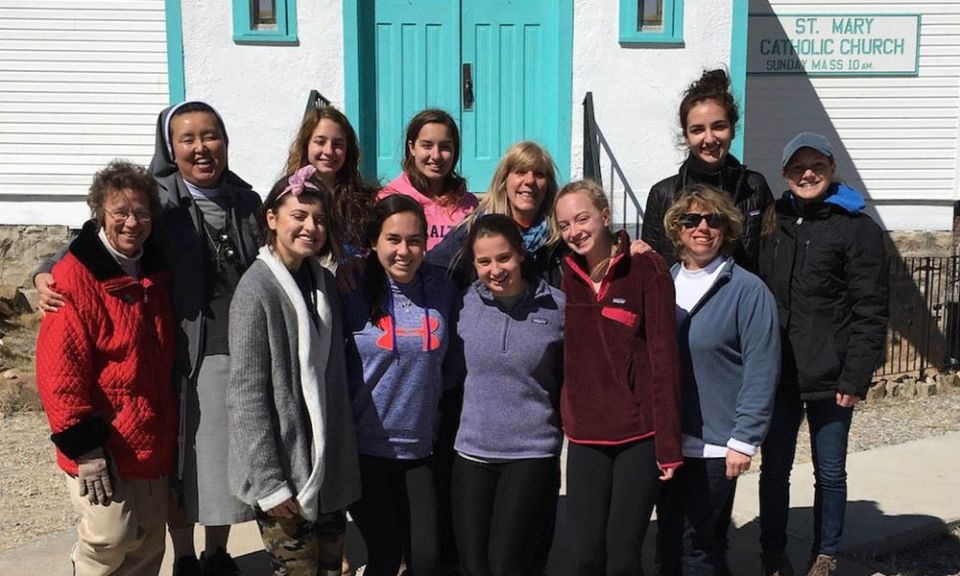 Sr. Patricia Bietsch, left (in red jacket) stands in front of St. Mary Mission church with students from Lauralton Hall, Our Lady of Mercy High School, in Milford, Connecticut, during their immersion trip in March 2017. (Provided photo)