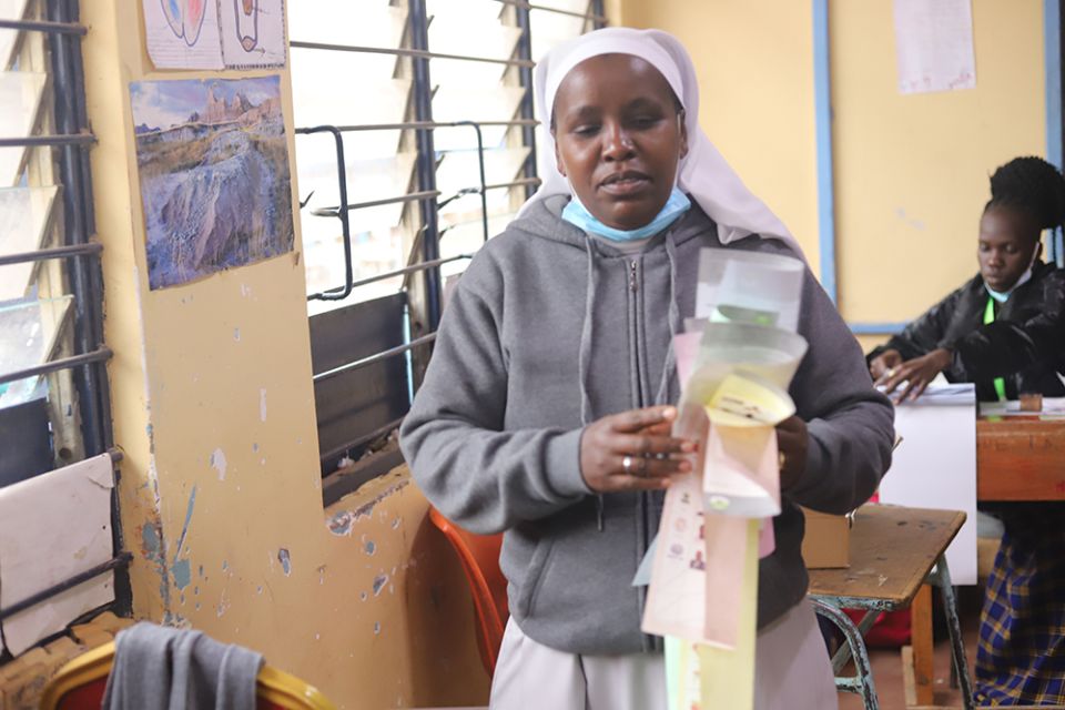 A religious sister carries her ballot papers to cast her vote at the Milimani Primary School polling station in Nairobi, Kenya. Most of the sisters are participating in the exercise to choose their next president and other leaders across the country. (GSR