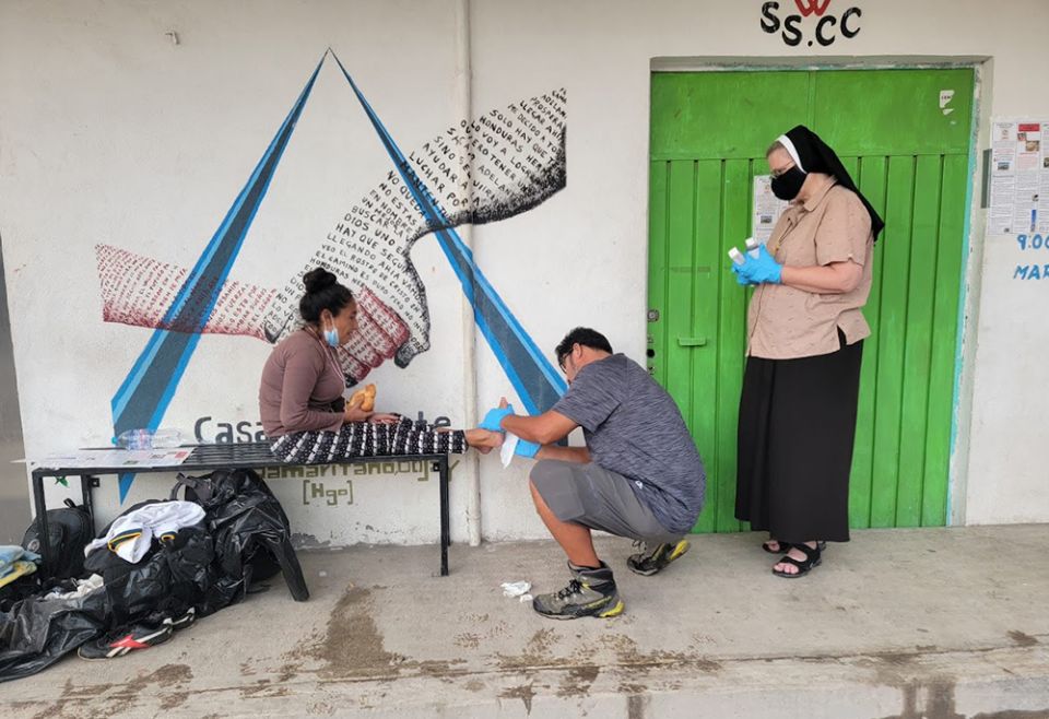 Aguilas volunteer Maurizio Vitela, with Sr. Marie Louise Edwards' assistance, helps clean a migrant's blisters. (Courtesy of Aguilas del Desierto)