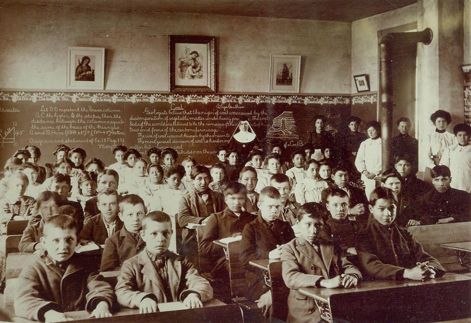 Sr. Macaria Murphy, a Franciscan Sister of Perpetual Adoration, poses with students and lay staff in a classroom at St. Mary's Catholic Indian Boarding School in Odanah, Wisconsin, in this undated photo. (Courtesy of FSPA)