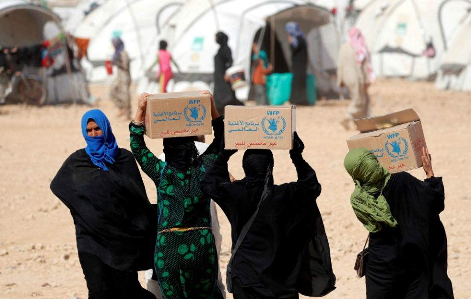 People displaced by fighting between the Syrian Democratic Forces and Islamic State militants carry boxes of food aid from the World Food Program at a camp in Ain Issa, Syria. (CNS/Reuters/Erik De Castro)