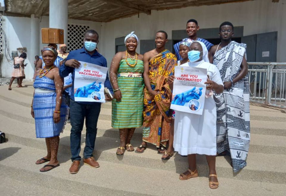 Sr. Dr. Lucy Hometowu, the COVID-19 vaccine campaign coordinator of the Sisters of Mary Mother of the Church medical team, poses for a photo with the youths at her local parish carrying a vaccine awareness flier in Ho Dome, Volta, Ghana. (Damian Avevor)