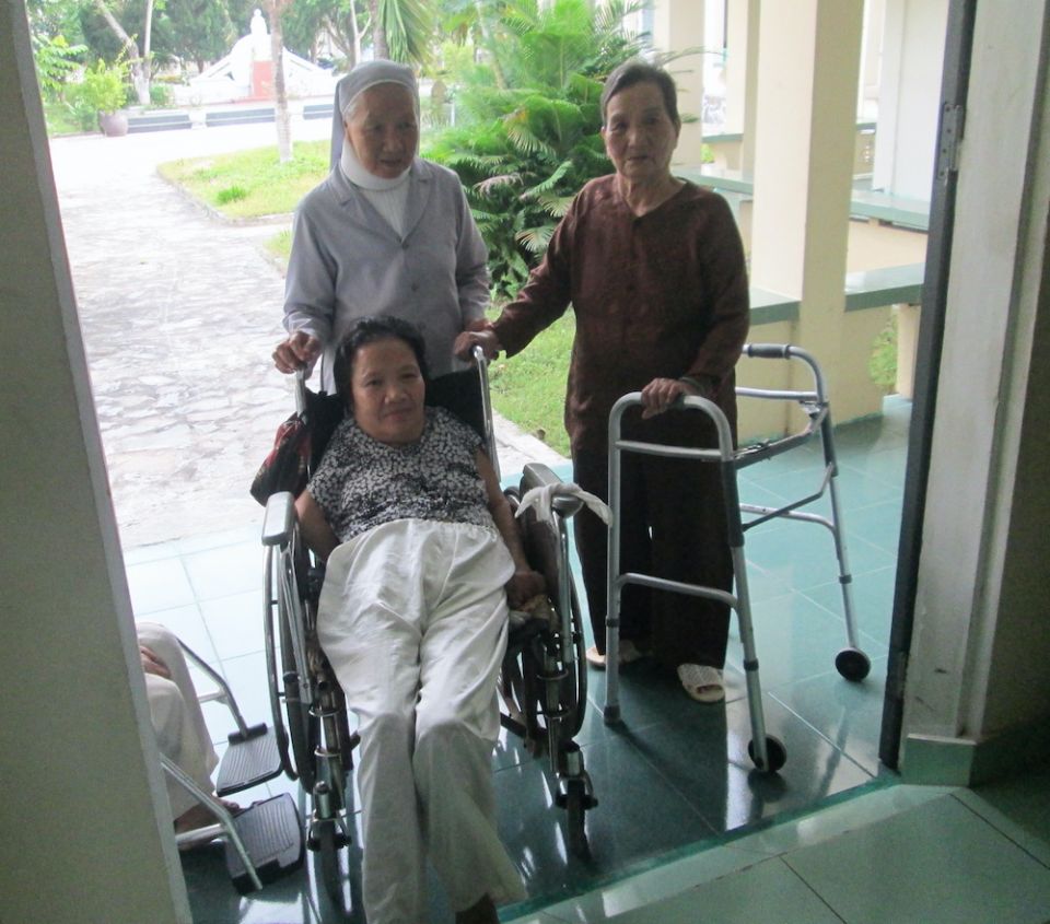 St. Paul de Chartres Sr. Léonard Huynh Thi An, top left, moves an elderly woman in a wheelchair into the chapel at the Elderly Loving Home in Da Nang, Vietnam. (Joachim Pham)