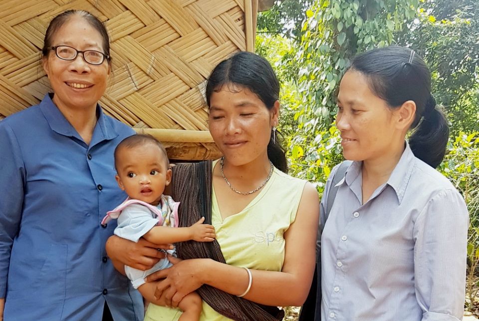Lovers of the Holy Cross of Hue Sr. Anna Nguyen Thi Hien, left, and another sister visit a Van Kieu ethnic woman, center, and her child in Cam Lo District of Quang Tri Province. (Joachim Pham)