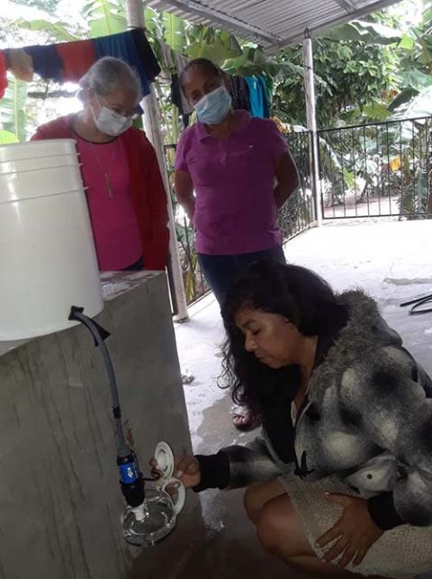 Maria Romero, a Congregation of Notre Dame associate, center, standing, demonstrates how to use a water filtration system to women in a community near Santa Barbara, Honduras, following the hurricanes. Clean drinking water is a priority in the disaster-hi