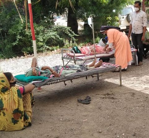 Sr. Tresa Kochumuttom tends to patients lying on cots kept under a tree outside Jyoti clinic. (Courtesy of Chetan Parmar)