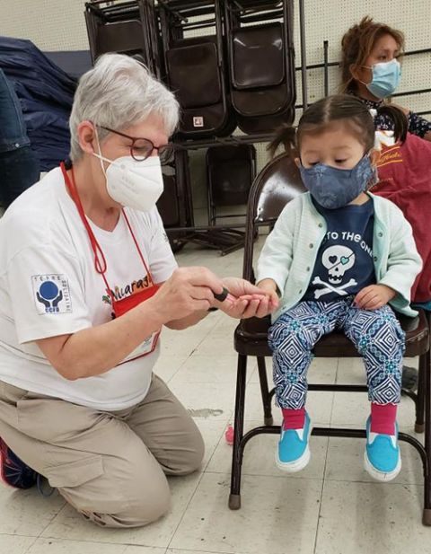 St. Joseph Sr. Sharon White paints the nails of a child at the Humanitarian Respite Center in McAllen, Texas. White said she felt the importance of affirming migrants' dignity with simple acts of kindness. (Courtesy of Sharon White)