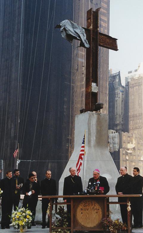 Archbishop Leonardo Sandri (at podium), says a prayer at ground zero in New York while laying a wreath at the site June 20, 2002. He was accompanied by Cardinal Edward Egan of New York (center left). (CNS/Chris Sheridan)