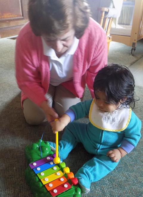 Dominican Sr. Jean Graffweg plays with a child at House on the Hill in Goshen, New York. She started out working at the facility's toddler room and now directs its migrant Head Start program. (Courtesy of Sisters of St. Dominic of Blauvelt, New York)