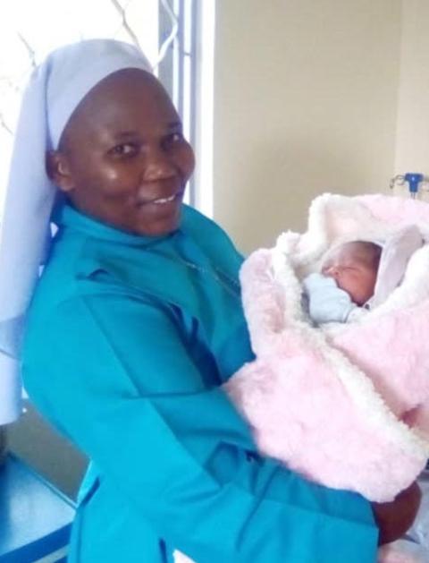 Good Samaritan Sister Evaline cradles the first baby to be born at St. Veronica Medical Centre in Ttomi Buloba, Uganda. (Courtesy of the Sisters of the Good Samaritan)