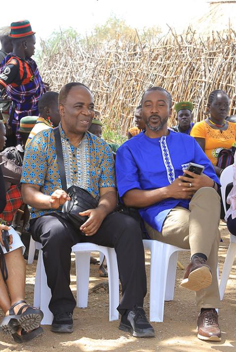 Dominican Fr. Aniedi Okure, left, and Steven Nabieu Rogers sit in chairs while visiting a rural community in Karamoja, Uganda. (Courtesy of Eucharia Madueke)