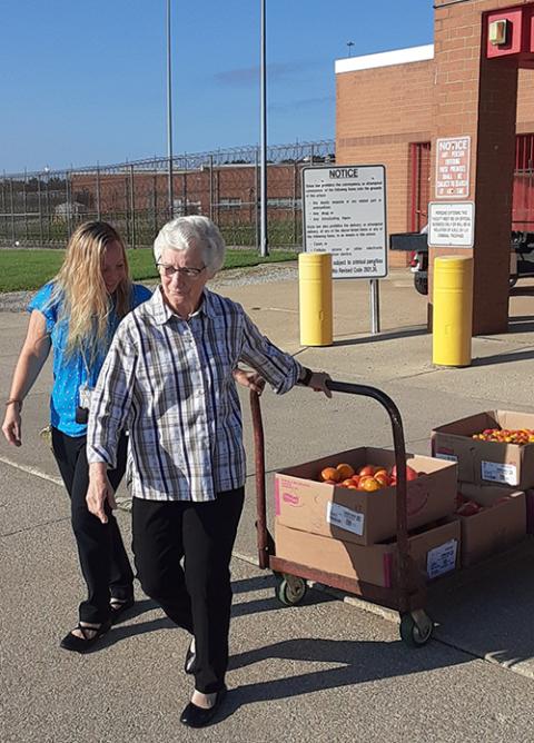 Notre Dame Sr. Rita Mary Harwood, assisted by Brooke Schramm, a correctional program specialist, wheels boxes of vegetables grown by inmates at the Grafton Correctional Institution. (Dennis Sadowski)