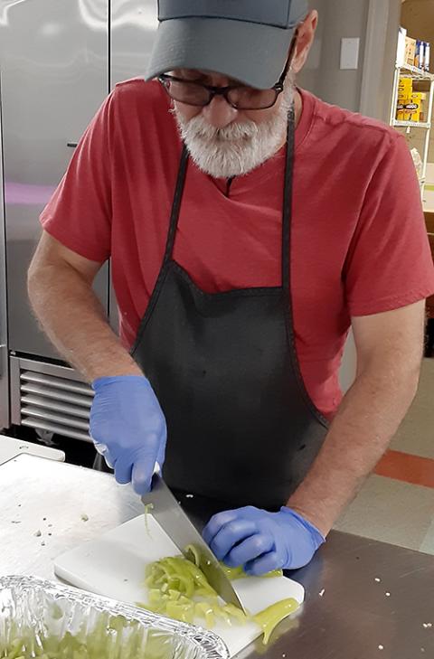 Mark Meloche, head cook at St. Elizabeth Center in Lorain, Ohio, cuts Hungarian peppers for a crostini topping on Aug. 29. (Dennis Sadowski)