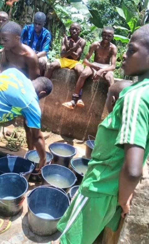 Students draw dirty water from a rain-soaked well at a school in Cameroon.