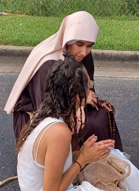 Sr. Neriáh of the Immaculate Conception prays with a community member during their street ministry.