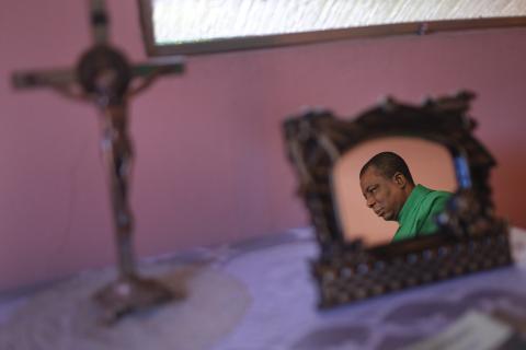 Photo of priest rests on table next to standing crucifix