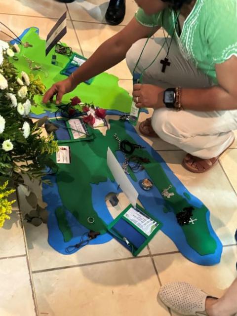 A member of CLAR places her crucifix on top of a piece of felt in the shape of Haiti in front of an altar before Mass at the Catholic University campus in Las Tres Rosas, Honduras, April 18.