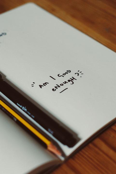 A notebook with the phrase "Am I good enough?" (Unsplash/Nik)