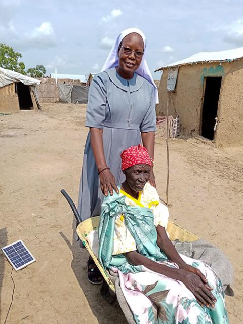 A Catholic sister helps transport an elderly woman in a wheelbarrow at a refugee settlement in el-Obeid, Sudan. (Courtesy of Sisters of the Sacred Heart of Jesus)
