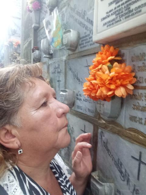 Cecilia Arenas dedicates a moment of silence in front of the funerary niche of her brother, Mario Alexander Arenas.