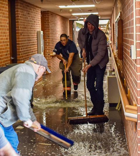Volunteers and an EMT help clear water in the hallway during the flooding at the monastery on Christmas 2022. (Courtesy of the Benedictine Sisters of Mount St. Scholastica)