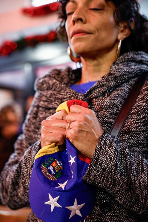 A woman prays while holding a hat in the colors of the Venezuelan flag, during a Mass for Venezuela held in Spanish at the Church of the Most Holy Redeemer in Rome Jan. 4, 2026. (OSV News/Reuters/Matteo Minnella)