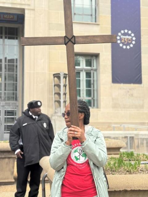 Maryknoll Sr. Susana Nchubiri holds a cross outside the U.S. Department of Justice in Washington April 3, 2026, during the Way of the Cross for peace and justice. Catholics and others sang and prayed at various federal buildings. (NCR photo/Rhina Guidos)