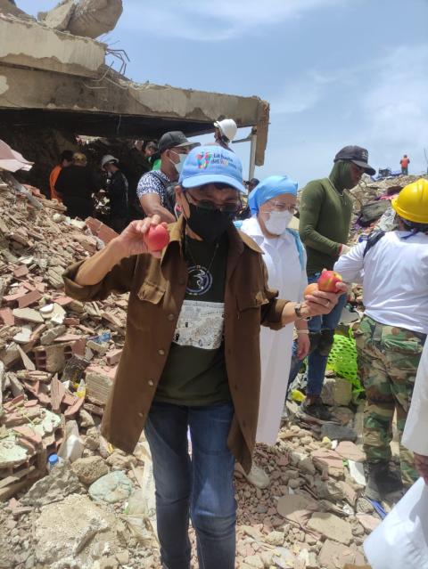 Convencida de que la esperanza también se siembra en los pequeños gestos, la Hna.  Emma Panizales reparte manzanas entre voluntarios, rescatistas y familiares en Catia La Mar, Venezuela, tras el terremoto del 24 de junio de 2026. (Foto: cortesía Carmen Camacho)