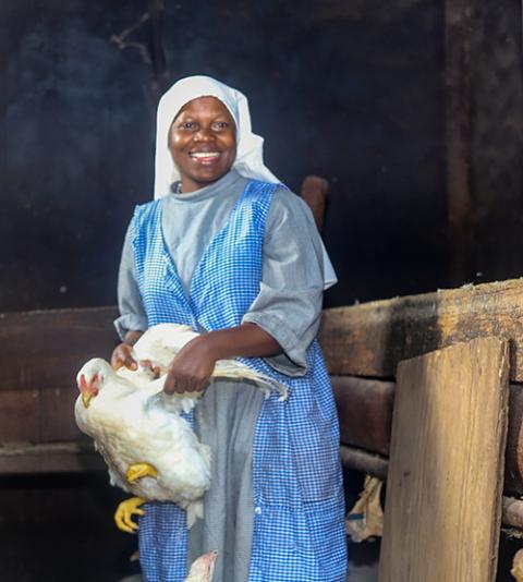 Sr. Geraldine Ghaife holds a chicken inside a structure once used for the sisters' biogas initiative at the Monastery of St. Dominic in Bambui, Cameroon. (GSR photo/Doreen Ajiambo)