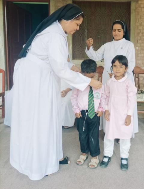 Dominican Sr. Shumail Yousaf, left, distributes rosaries to students for performing at the national pilgrimage in Mariamabad, near Lahore, Pakistan. (Courtesy of Cecilia Rasheed)
