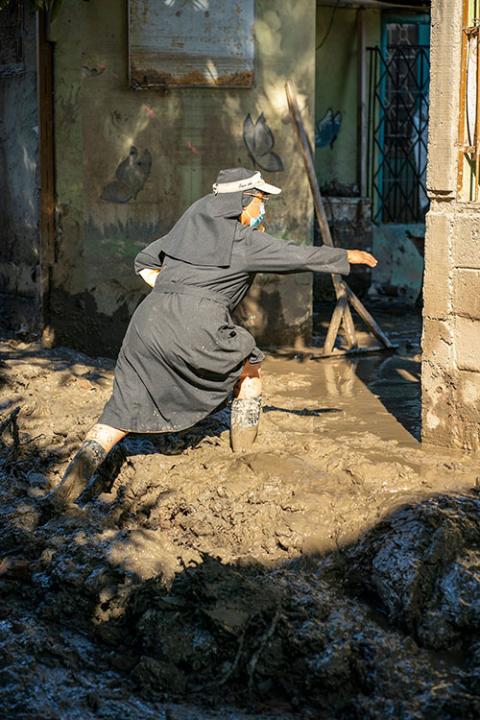 Sr. Milena Vanegas navigates the mud-covered streets of La Planeta, a neighborhood of La Lima, Honduras, in January. (Gregg Brekke)