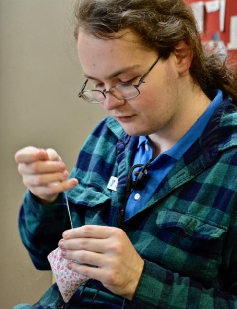 YMCA Safe Place Services staff member Roan Head sews hand warmers for the day shelter's clients in Louisville, Kentucky. (GSR photo / Dan Stockman)