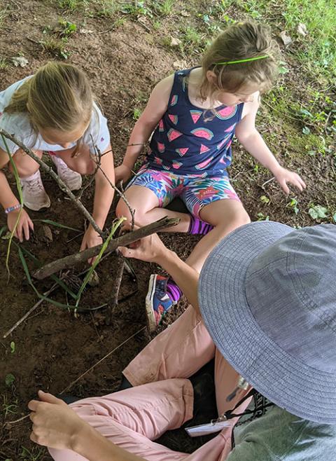 Julia Gerwe (bottom right) engages students of the St. Joseph Montessori Children's Center in Bardstown, Kentucky, in nature play, fostering their connection to nature and to place. (Courtesy of Jane Rudnick) Julia Gerwe (bottom right) engages students of the St. Joseph Montessori Children's Center in Bardstown, Kentucky, in nature play, fostering their connection to nature and to place. (Courtesy of Jane Rudnick)