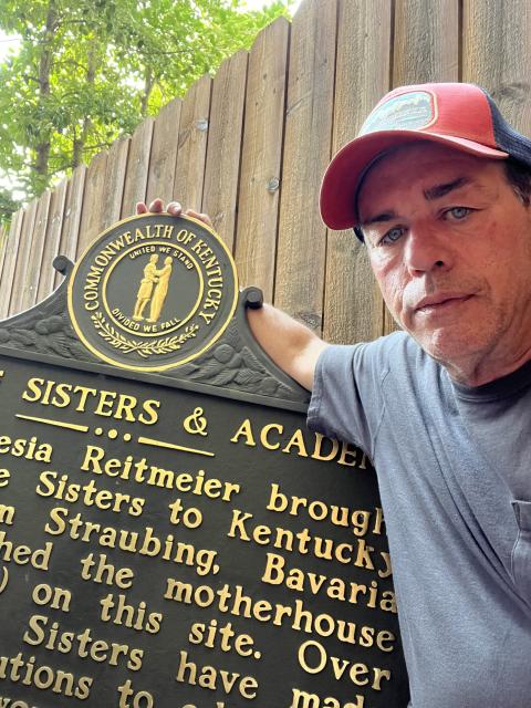 Todd Abell, a volunteer with Louisville Outreach to the Unsheltered, poses with the Ursuline Sisters of Louisville's historic marker, which he found abandoned about three blocks from where it should have been standing.